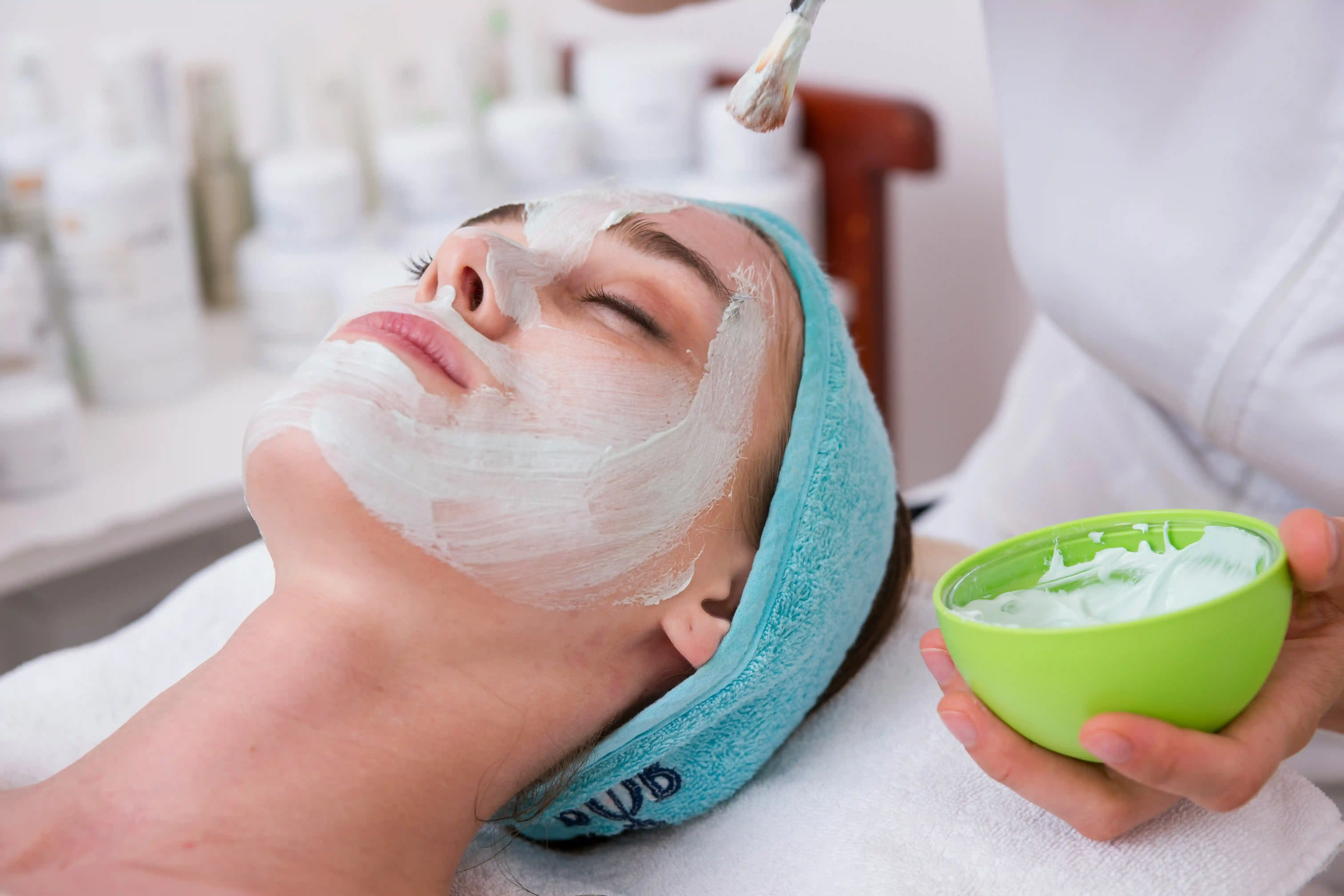 Professional esthetician applying a customized facial mask during spa treatment